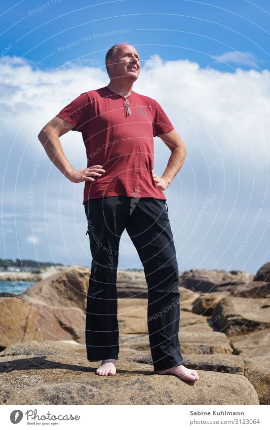 Urlaub Mensch maskulin Mann Erwachsene 1 45-60 Jahre Natur Himmel Sommer Schönes Wetter Küste Bekleidung T-Shirt Hose Stein beobachten Blick stehen einfach