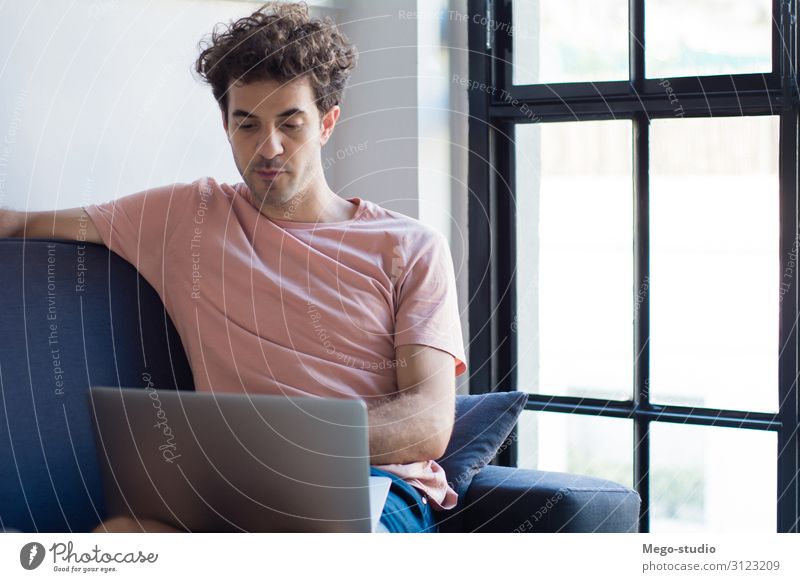 Junger Mann entspannt sich auf dem Sofa mit einem Laptop. Lifestyle Freude Glück Leben Erholung ruhig Freizeit & Hobby lesen Wohnung Haus