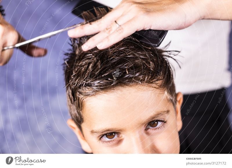 Der schöne Junge lässt sich mit der Schere die Haare schneiden. Lifestyle Stil Körperpflege Haare & Frisuren Kinderzimmer Arbeit & Erwerbstätigkeit Beruf