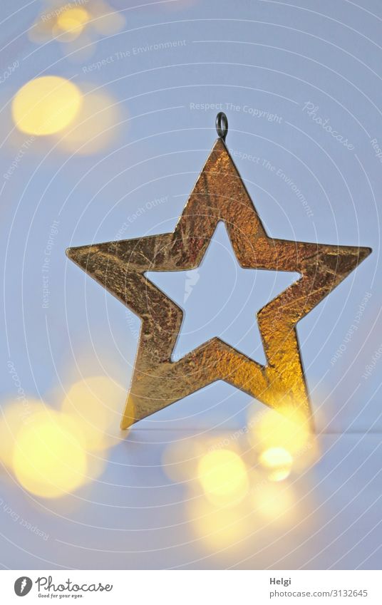 goldener Stern als Dekoration vor hellblauem Hintergrund mit leuchtendem Bokeh Weihnachten & Advent Dekoration & Verzierung Zeichen Stern (Symbol) glänzend