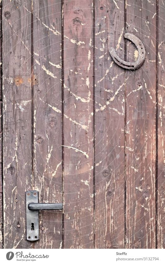 alte Zeiten mit Holz und Eisen Aberglaube Holztür Eingangstür Schutz Volksglaube Hufeisen Glück Symbol Schuppentür Tür Türschloss verwittert Glückssymbol betagt