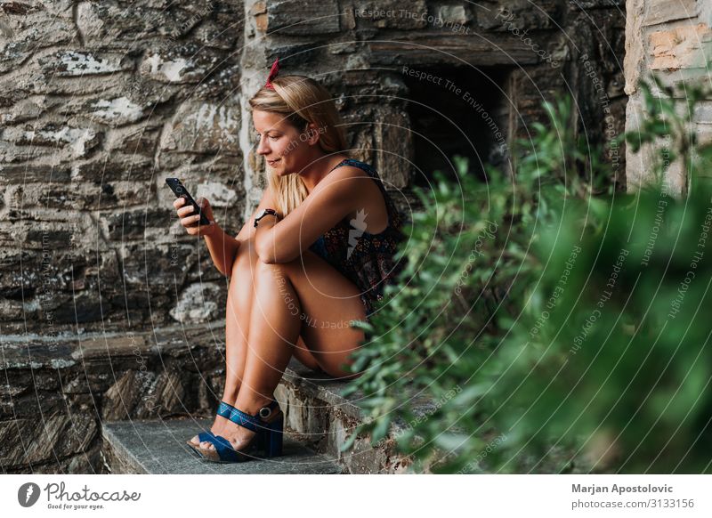 Junge Frau mit Smartphone auf der Treppe sitzend Lifestyle Freizeit & Hobby Sommer Sommerurlaub Handy Technik & Technologie Telekommunikation feminin