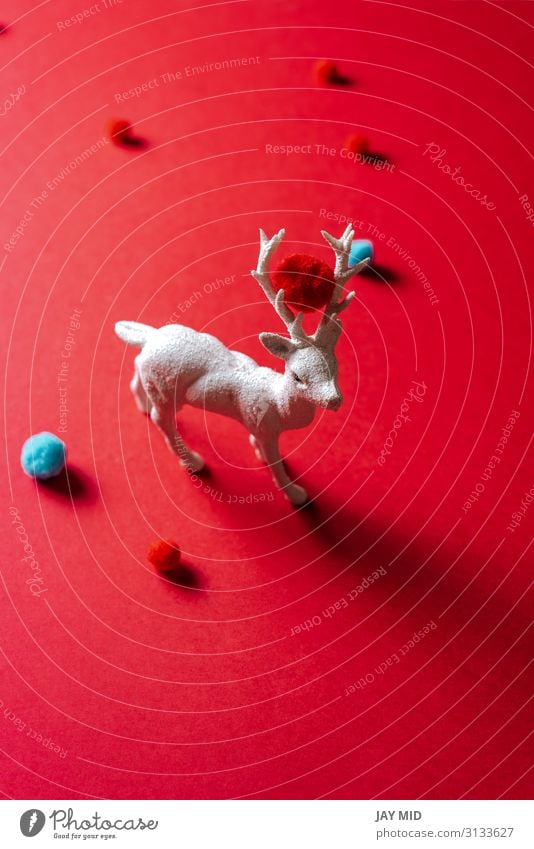 Weißes Rentierspielzeug mit kleinen Wollknäueln auf rotem Hintergrund Winter Dekoration & Verzierung Feste & Feiern Weihnachten & Advent Kunst Tier Mode