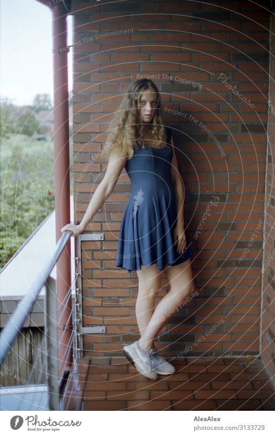 Junge Frau steht auf einem Balkon von Ziegelsteinmauer Lifestyle Stil schön Wohlgefühl Häusliches Leben Backsteinwand Geländer Jugendliche 18-30 Jahre