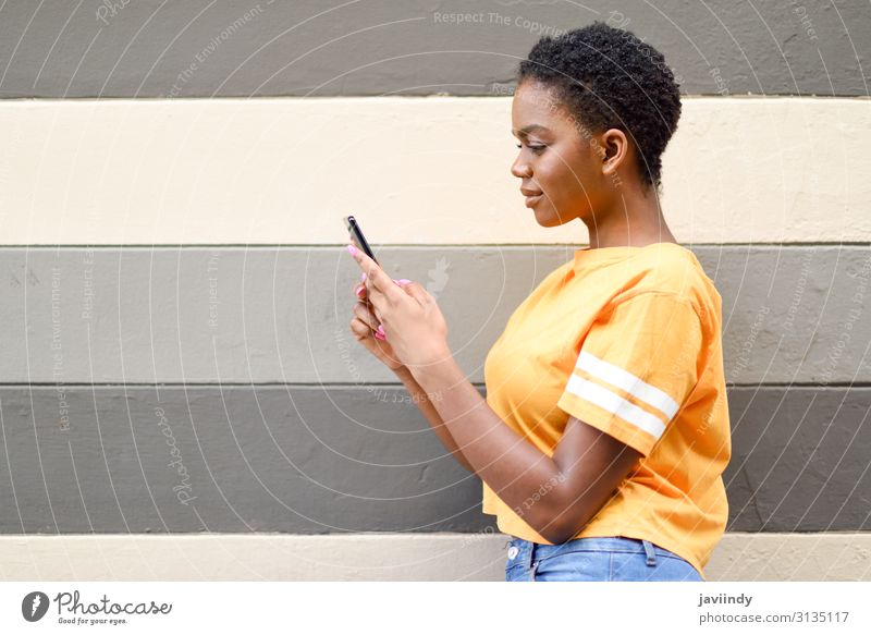 Junge schwarze Frau, die ihr Smartphone im Freien benutzt. Lifestyle Stil Glück Haare & Frisuren Telefon Handy PDA Technik & Technologie Internet Mensch feminin