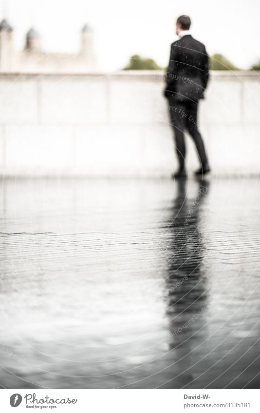 jemanden im Regen stehen lassen - Geschäftsmann steht im Regen ... auf der nassen Straße spiegelt sich sein Schatten Business businessmann Mann
