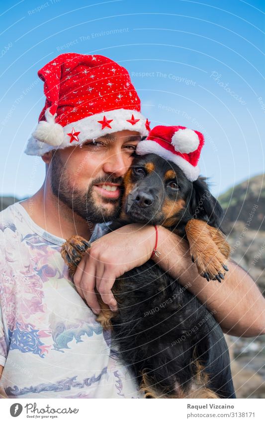 Mann und sein Hund mit Weihnachtsmützen. Freude Winter Weihnachten & Advent Erwachsene Freundschaft 1 Mensch 30-45 Jahre Tier Hut Haustier Liebe niedlich blau