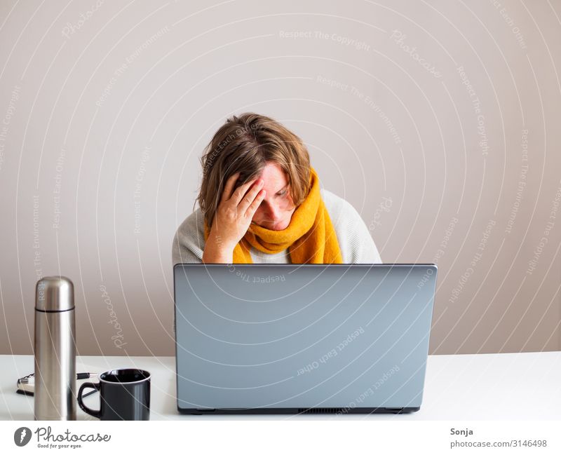 Frau mit gelben Schal und Kopfschmerzen bei der Arbeit, Grippezeit Büroarbeit feminin Erwachsene Leben 45-60 Jahre Thermoskanne Tasse Computer Stress Unlust