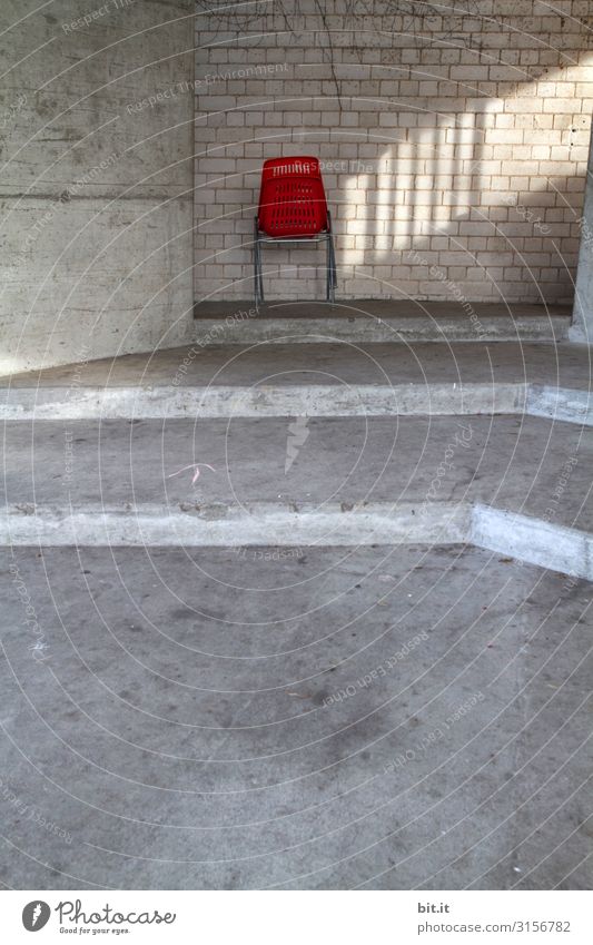 Roter Stuhl aus Plastik, mit Lichteinfall vor Mauer. Bauwerk Gebäude Architektur Wand Treppe Fassade Stein Beton Linie Pfeil Streifen sitzen Sonnenlicht einzeln
