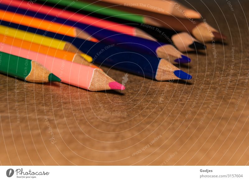 Farbige Buntstifte liegend auf braunem Untergrund | Firlefanz Schreibwaren Zettel Farbstift Schreibstift zeichnen blau mehrfarbig gelb grün violett orange rosa