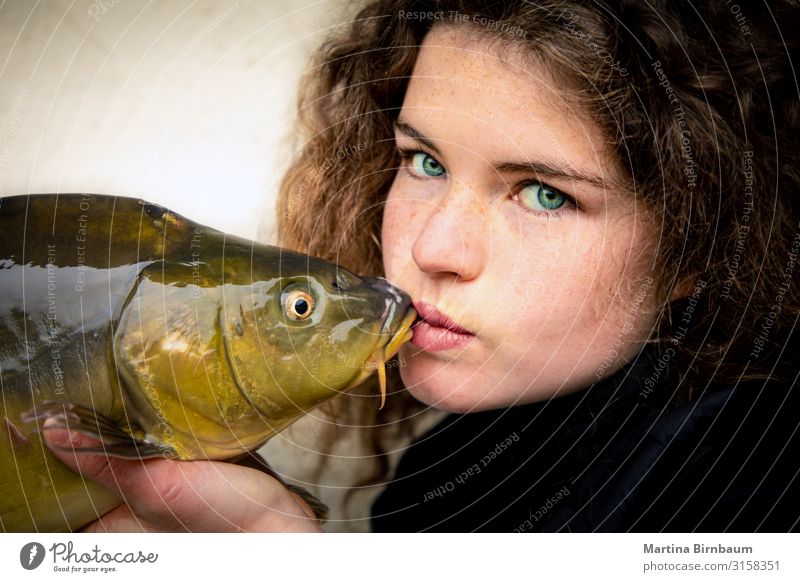 Junge Frau mit eindrucksvollen grünen Augen, die einen Karpfen, Fisch und andere Tiere küssen. Meeresfrüchte Abendessen Lifestyle Glück schön Gesicht Angeln
