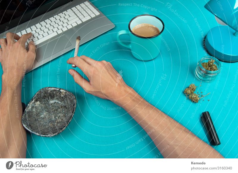Rauchen eines Marihuana Joint während der Arbeit an einem blauen Tisch. Kräuter & Gewürze Frühstück Heißgetränk Kaffee Espresso Tasse Becher Lifestyle Reichtum