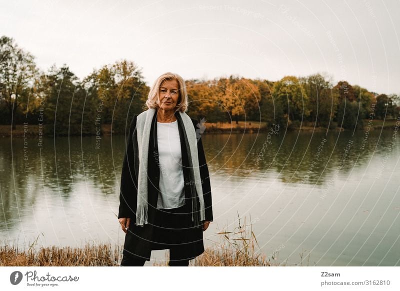 TRAUDL Lifestyle elegant Stil Frau Erwachsene Weiblicher Senior 45-60 Jahre Natur Landschaft Herbst Schönes Wetter See Mode Mantel Schal blond Blick Coolness