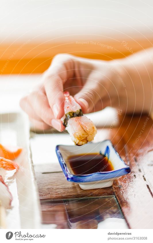 Hand Mädchen taucht ein Stück Sushi auf Sojasauce. Abendessen Teller Tradition Asien Sortiment Bonito Essen zubereiten Speise Filet Fisch Ingwer Feinschmecker
