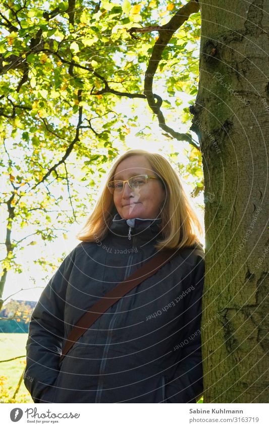 Innehalten Mensch feminin Frau Erwachsene 1 45-60 Jahre Natur Sonnenlicht Herbst Schönes Wetter Baum Wald Jacke blond Scheitel Erholung Lächeln stehen einfach