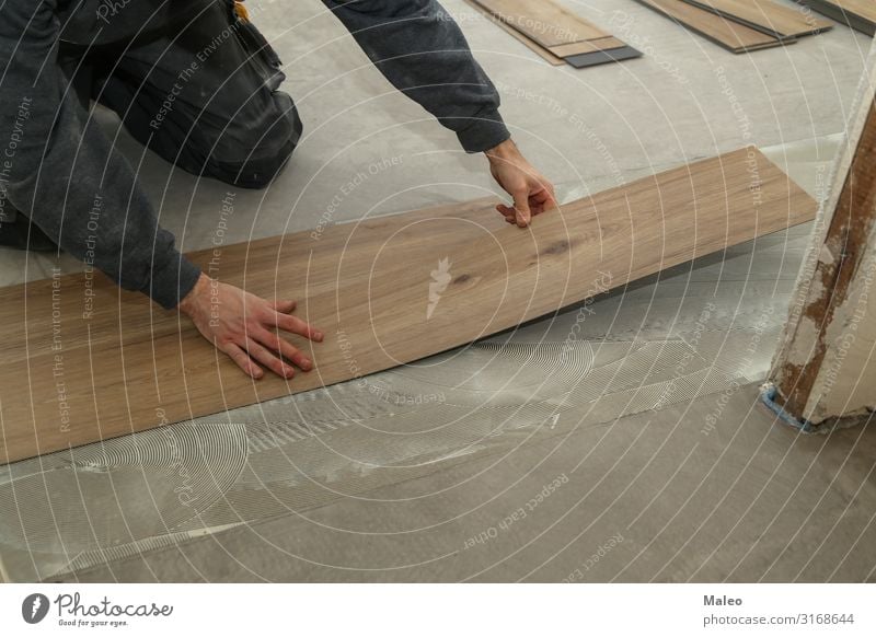 Ein Arbeiter installiert neuen Vinylfliesenboden Mann Baustelle Reparatur Haus Wohnung Bodenbelag Fliesen u. Kacheln Installationen Material Schallplatte