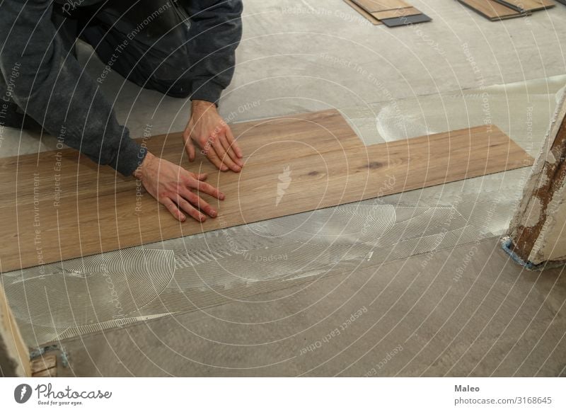 Ein Arbeiter installiert neuen Vinylfliesenboden Mann Baustelle Reparatur Haus Wohnung Bodenbelag Fliesen u. Kacheln Installationen Material Schallplatte