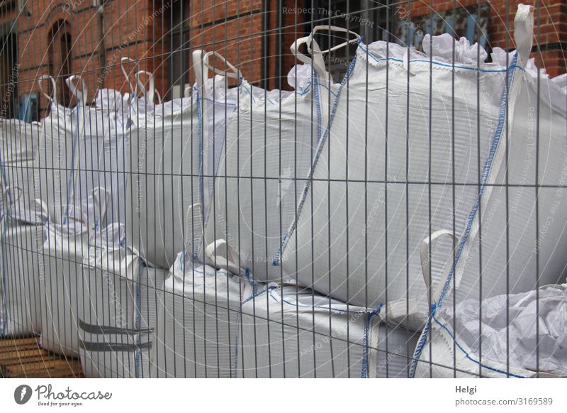 große gefüllte weiße Kunsstoffsäcke stehen aufeinander hinter einem Bauzaun Hamburg Hafenstadt Mauer Wand Sack Zaun Stein Metall Kunststoff Linie festhalten