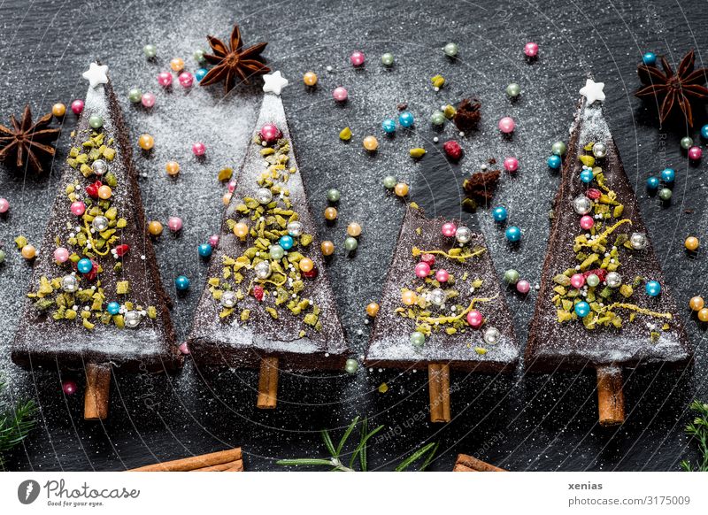vier weihnachtlich dekorierte Tannenbäume aus Schokoladenkuchen mit Zuckerperlen, Sternanis und Zimtstangen Kuchen Weihnachten & Advent Tannenbaum Lebensmittel