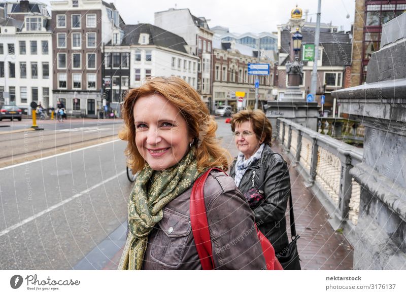 Zwei Frauen mittleren Alters, die auf der Brücke in Amsterdam stehen. Lifestyle Ferien & Urlaub & Reisen Tourismus Erwachsene Wolken Stadtzentrum Straße Lächeln