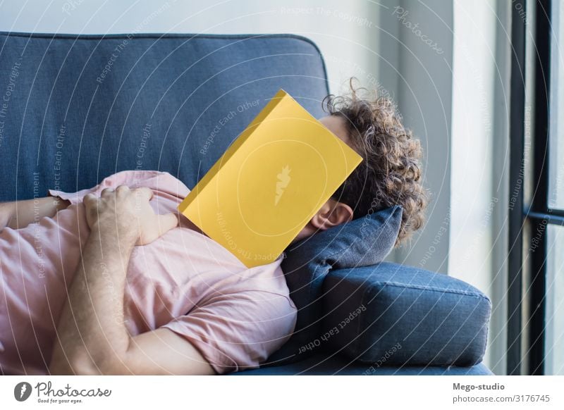Mann schläft auf Sofa mit Buchdeckel im Gesicht Lifestyle Stil Glück Erholung Freizeit & Hobby lesen Haus Business Mensch Erwachsene schlafen weiß Müdigkeit