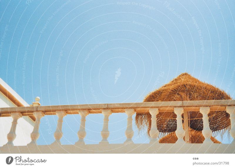 Sonnendeck Balkon Sommer Ibiza Stroh Sonnenschirm Sonnendach Physik Architektur Geländer Himmel blau Wärme