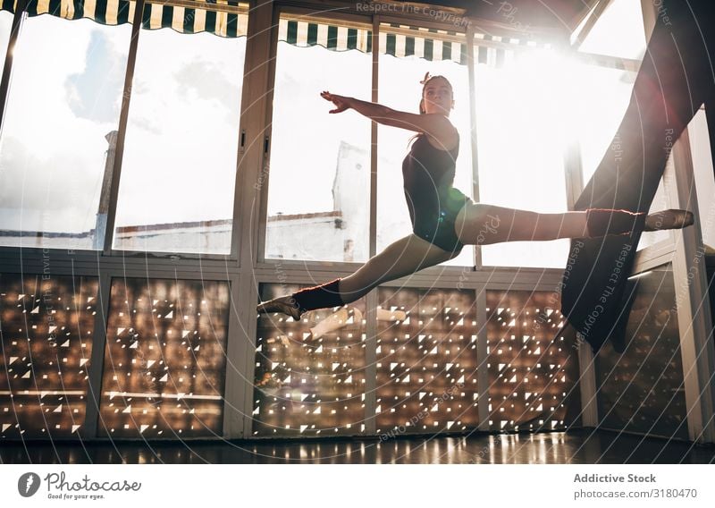 Junge schlanke Ballerina, die in Studiobeugebeinen über Grund springt. Frau springen Spagat Balletttänzer Pose Bewegung Akrobatik Turnen Tänzer Tanzen