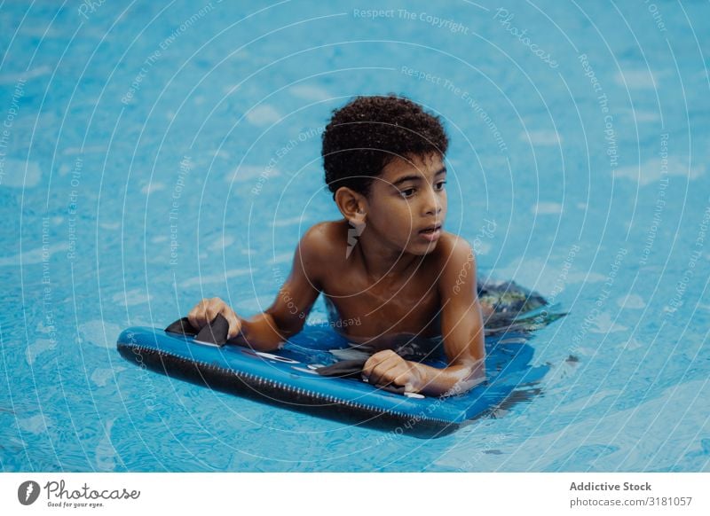 Schwarzer Junge schwimmt im Pool Schwimmbad Schwimmsport Wegsehen schwarz Sommer Glück Freude Wasser Ferien & Urlaub & Reisen Kind Afroamerikaner urwüchsig