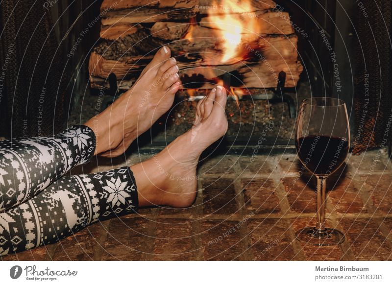 Frau ruht sich bei einem Glas Rotwein am Kamin aus. Alkohol Lifestyle Erholung Freizeit & Hobby Winter Haus Weihnachten & Advent Erwachsene Hand Wärme dunkel
