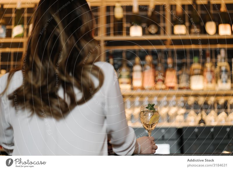 Rückansicht einer anonymen Frau, die einen Cocktail in der Bar hält. Restaurant gemütlich Party Alkohol Nacht Feste & Feiern Lifestyle Freizeit & Hobby ruhen