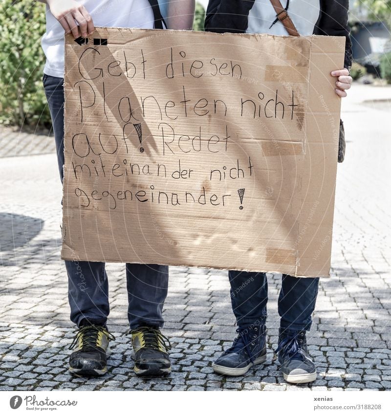 Weltschmerz / zwei Jugendliche stehen auf der Straße und halten beschrifteten Karton in den Händen für fridays for future - Demonstration - Gebt diesen Planeten nicht auf! Redet miteinander nicht gegeneinander!