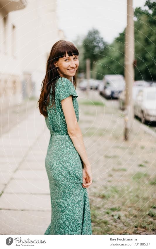 Eine Frau in einem eleganten grünen Kleid dreht sich um und lächelt in die Kamera Erwachsener attraktiv schöne Frau charmant schick Großstadt klassisch