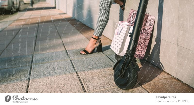 Elektroroller mit Einkaufstaschen und Frau im Hintergrund. kaufen elegant Stil Internet Mensch Erwachsene Fuß Verkehr Straße Mode modern Rad ökologisch Öko