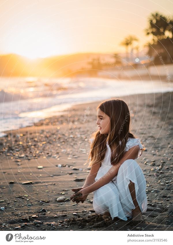 Liebenswertes Mädchen spielt mit Sand am Strand. Spielen reizvoll Seeküste Sonnenlicht niedlich Sonnenuntergang Kind Kindheit Porträt besinnlich träumen Küste