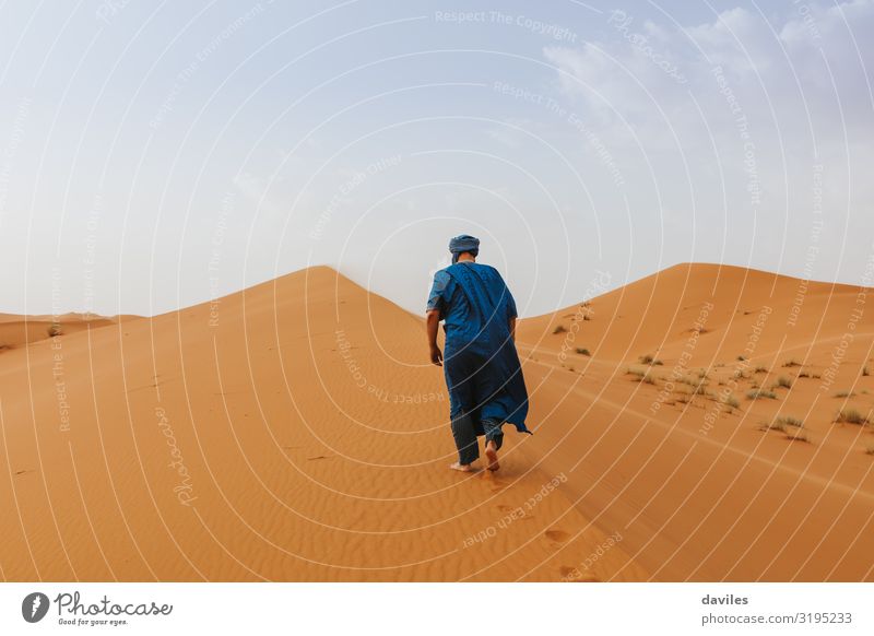 Ein arabischer Mann in blauer Kleidung läuft auf einer Wüstendüne. Lifestyle elegant Stil exotisch Ferien & Urlaub & Reisen Tourismus Ausflug Abenteuer Mensch