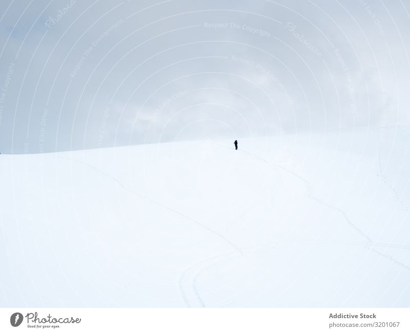 Unbekannter einsamer Reisender beim Spaziergang auf einem verschneiten Hügel Einsamkeit Inspiration Schnee minimalistisch Landschaft Natur Berge u. Gebirge