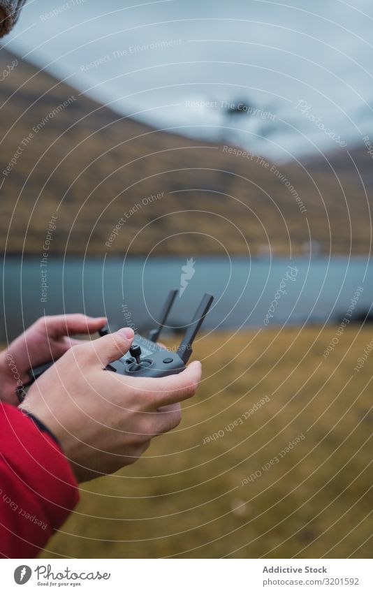 nicht erkennbare Person, die eine Drohne in der Nähe des Sees auf den Färöern kontrolliert abgelegen Technik & Technologie Kontrolle Dröhnen Innovation Radio
