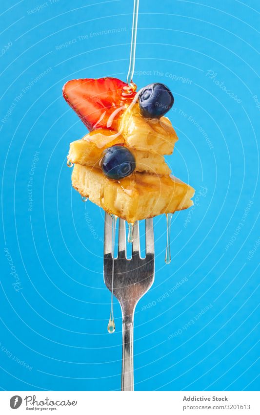 Appetitanregendes Obstdessert mit Honig auf der Gabel Dessert appetitlich Frucht Zusammensetzung süß Erdbeeren Blaubeeren aromatisiert blau Lebensmittel lecker