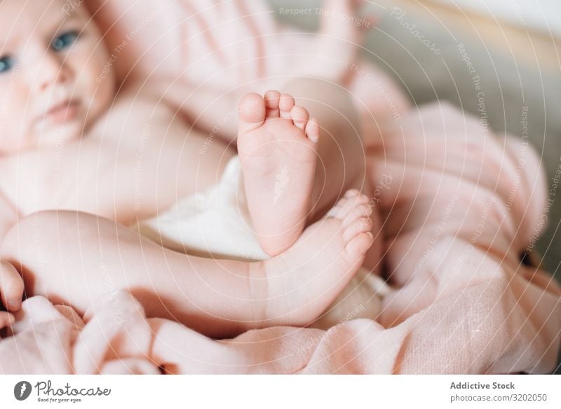 Süßes, liegendes und spielendes Baby mit prallen Beinen Fuß klein Decke Säuglingsalter niedlich gestrickt neugeboren Spielen Freude erkundend schön heiter