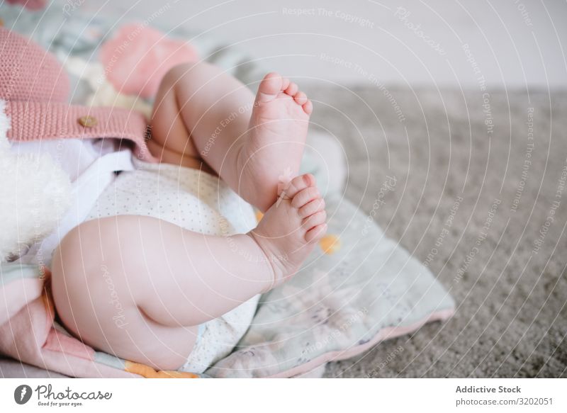 Süßes, liegendes und spielendes Baby mit prallen Beinen Fuß klein Decke Säuglingsalter niedlich gestrickt neugeboren Spielen Freude erkundend schön heiter