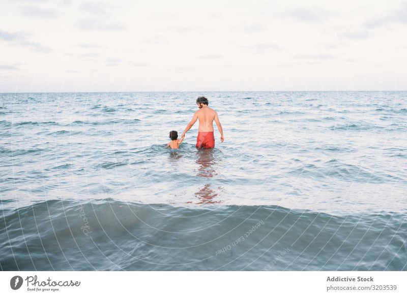 Vater mit Sohn im Wasser laufend Mann Im Wasser treiben Küste Zusammensein Händchen haltend Junge Familie & Verwandtschaft Aktion Strand