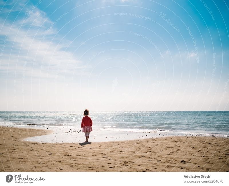 Mädchen, das am sonnigen Tag am Strand spazieren geht laufen Sonnenstrahlen Kleinkind Sand Seeküste Wasser ruhig Küste Kindheit Ferien & Urlaub & Reisen Aktion