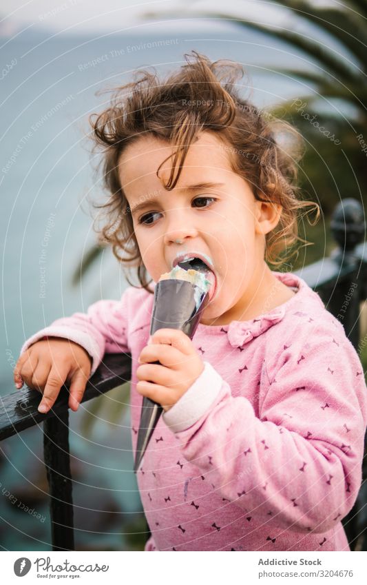 Bezauberndes ernstes Kleinkind-Mädchen mit Eiscreme Speiseeis reizvoll charmant besinnlich Essen Porträt Kindheit unschuldig Dessert süß Lebensmittel