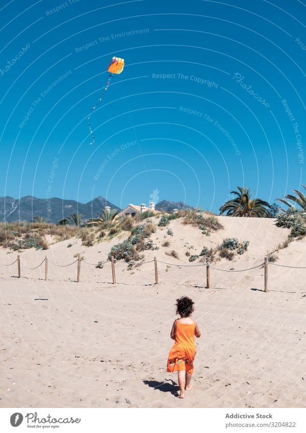 Kleinkind spielt mit Drachen am Sandstrand Mädchen Lenkdrachen Strand Spielen klein Kind Frau fliegen Blauer Himmel rennen Seeküste Ferien & Urlaub & Reisen