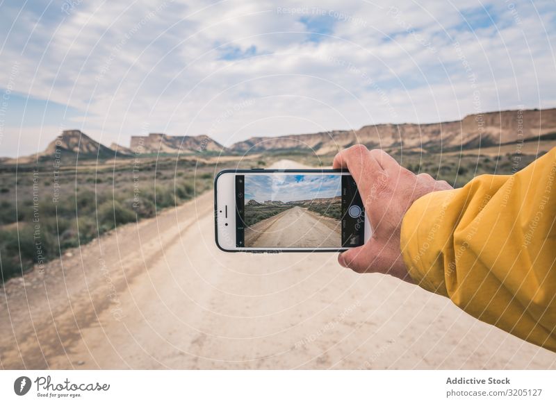 Person, die eine leere Straße und Wüstenlandschaft fotografiert Mann fotografierend Hügel Landschaft Sand Stein Pflanze Ausflug PDA regenarm Natur Himmel