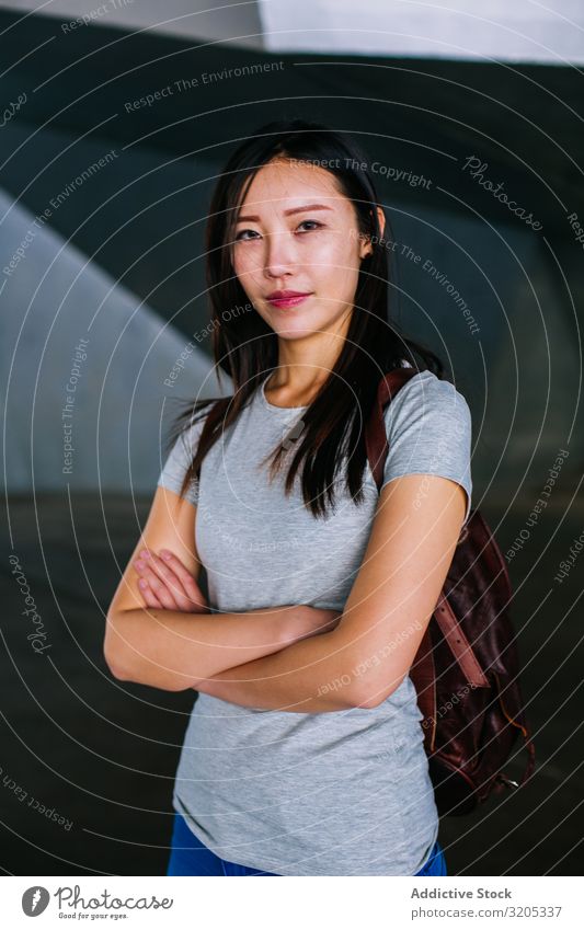 Selbstbewusste asiatische Frau schaut in die Kamera heiter positiv verschränkte Arme Lächeln Stadt lässig Jugendliche Glück U-Bahn Durchgang Großstadt