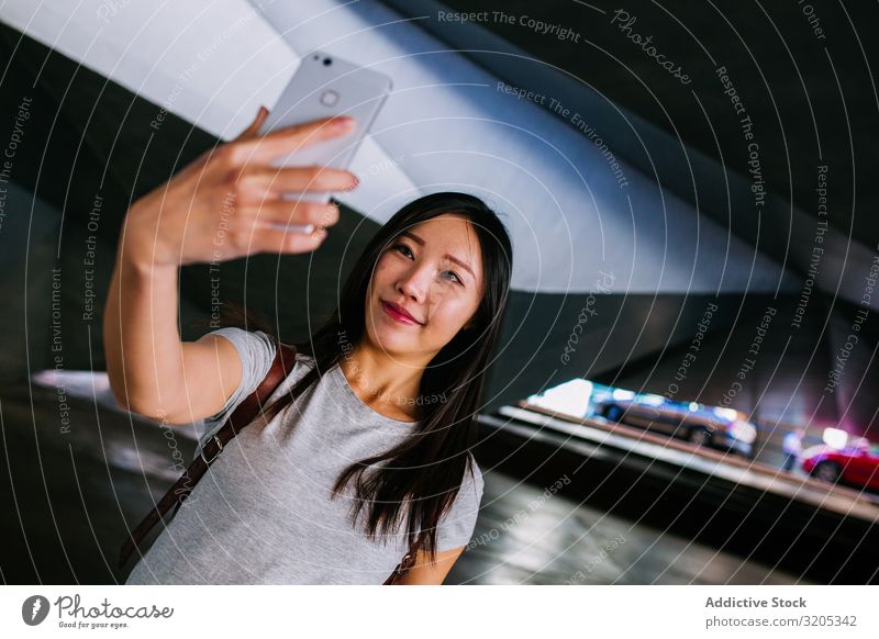Asiatische Frau nimmt sich in der Untergrundpassage selbst ein Selfie U-Bahn Durchgang Körperhaltung Lächeln asiatisch Jugendliche PDA lässig Stadt schäbig