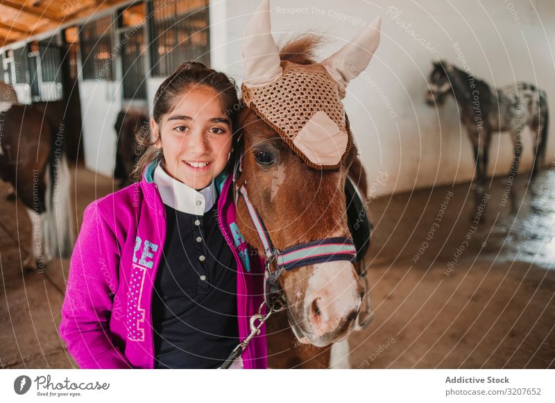Mädchen mit entzückendem Pony mit Hut Ponys Pferdestall Tier in die Kamera schauen Kind Porträt Umarmen Freund Haustier Kindheit Landschaft Kraulen wenig