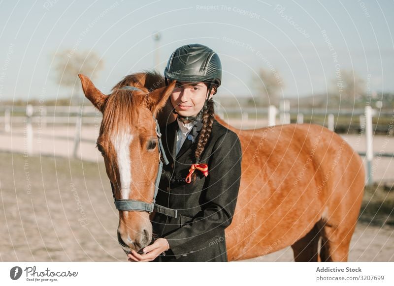 Frau im Jockey-Outfit mit Pferd stehend Kraulen Tier Reiterin Teenager jung Haustier Freund Liebe Streicheln Schutzhelm berühren schön Pflege Säugetier