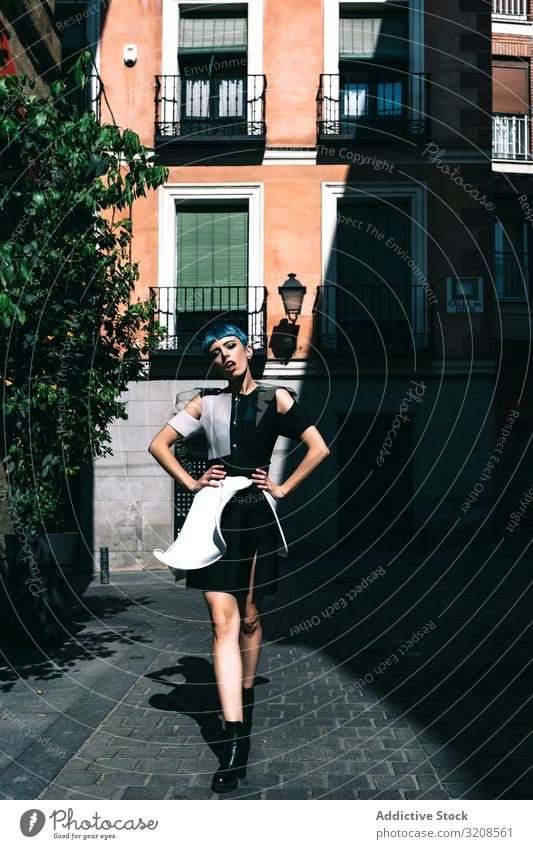 Selbstbewusste Frau in futuristischer Kleidung auf der Straße Großstadt trendy Model Kontrast selbstbewusst Gebäude Straßenbelag Hände an der Taille jung Stil
